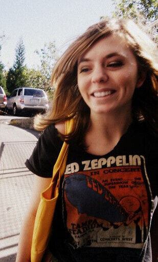 Shelby Dennis, your freelance beauty copywriter, circa 2010. Smiling in the sunshine and wearing a Led Zeppelin t-shirt.