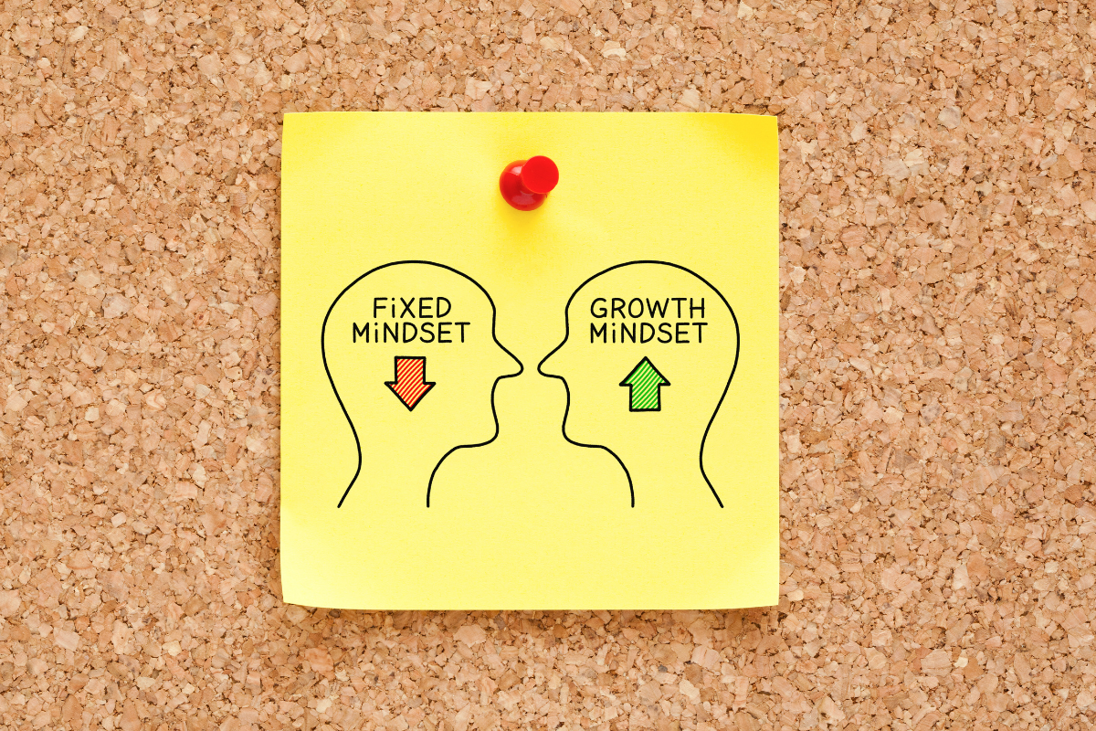 Sticky note with "fixed mindset" and red arrow pointing down. Sticky note with "growth mindset" and green arrow pointing up.